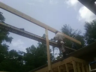 Carpenter setting a ridge beam over a new addition frame — Ice Dam Removal by Roofing Brothers in Wellfleet