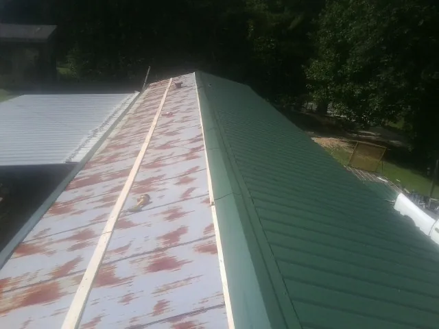 Old rusted panels beside newly installed green metal roofing — Wind Damage Roof Repair by Roofing Brothers in Wellfleet