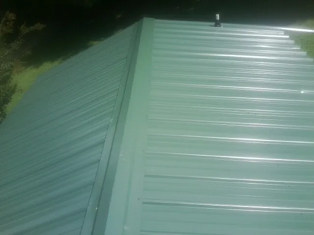 New green metal panels meeting at the ridge of a roof — Flat Roof Repair work by our crew in Wellfleet