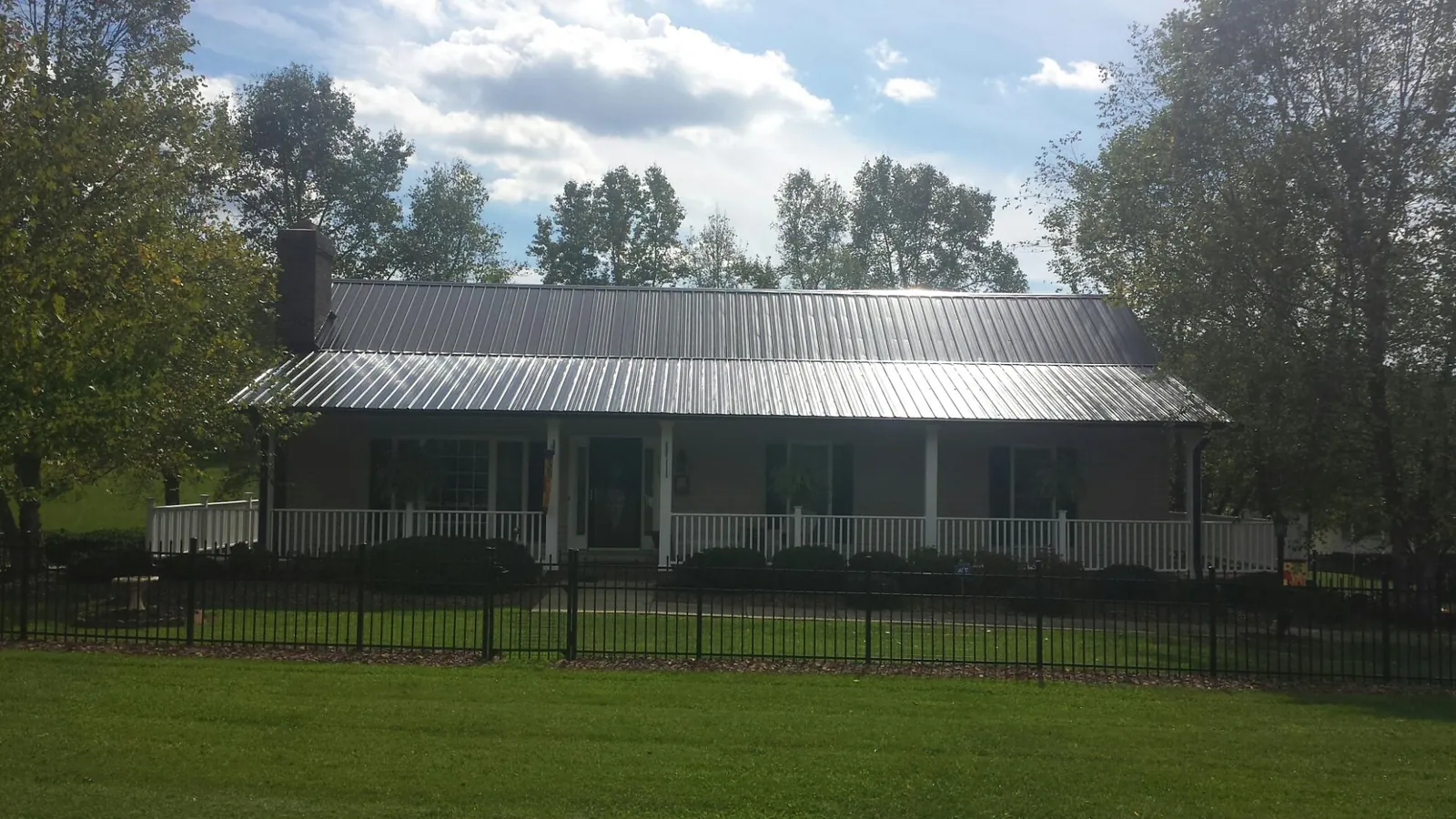 Gray metal roof on a brick ranch with a full width front porch — Gutter Guard Installation work by our crew in Wellfleet