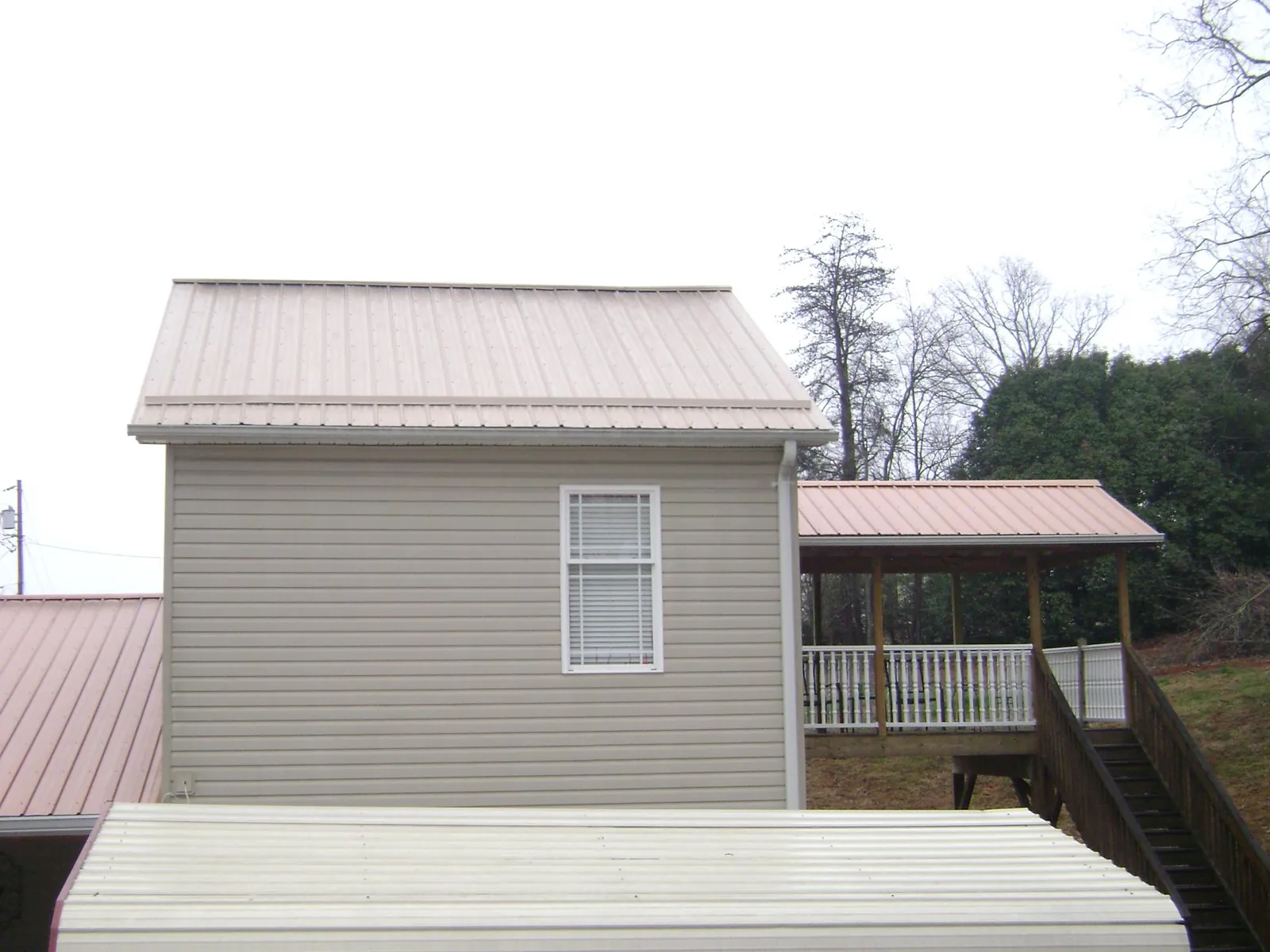Tan metal roofs on a two story addition and attached porch, from a Roof Replacement job in Wellfleet